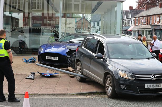 Driver mounts car onto £200,000 Aston Martin outside dealership after 'losing control'